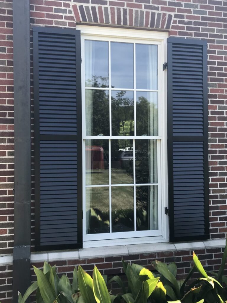 Black exterior shutter on brick house