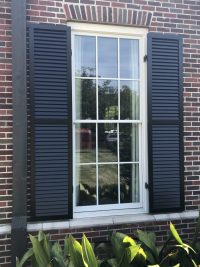 Black exterior shutter on brick house